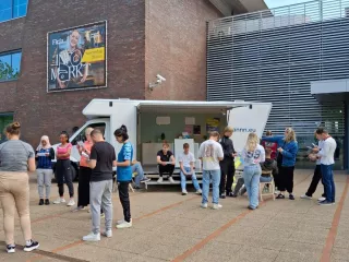 Een afstandsfoto van de Gezonde Huiskamer buiten met studenten eromheen